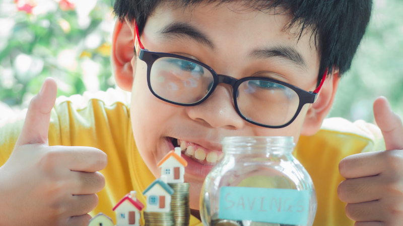Trẻ em bỏ tiền vào ống tiết kiệm để học cách tiết kiệm tiền như người Nhật